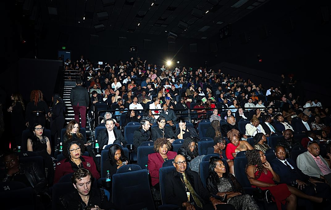 A festival audience laughing together in a darkened theater during a screening.